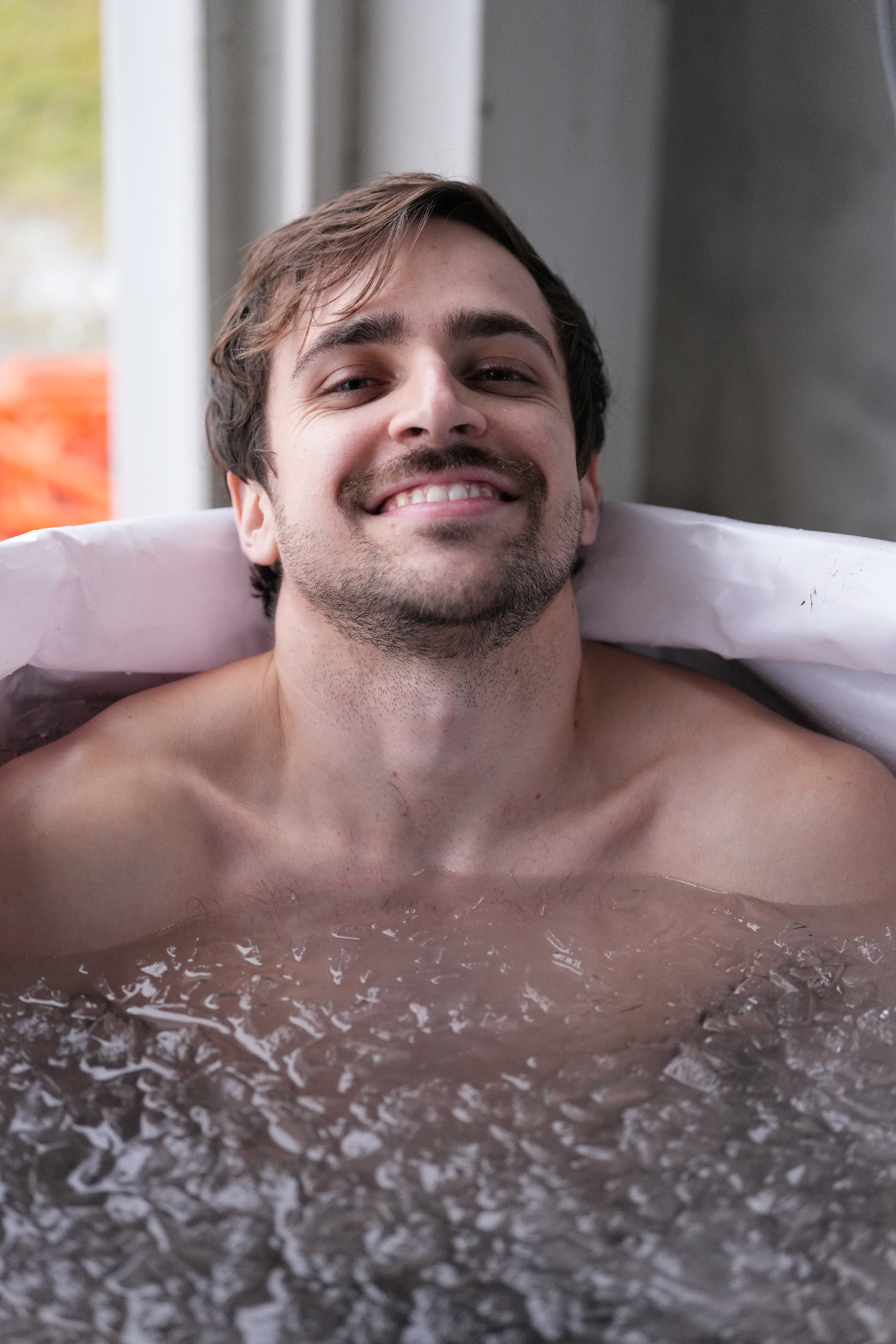 Participante sorrindo dentro da banheira de gelo durante a experiência de recovery