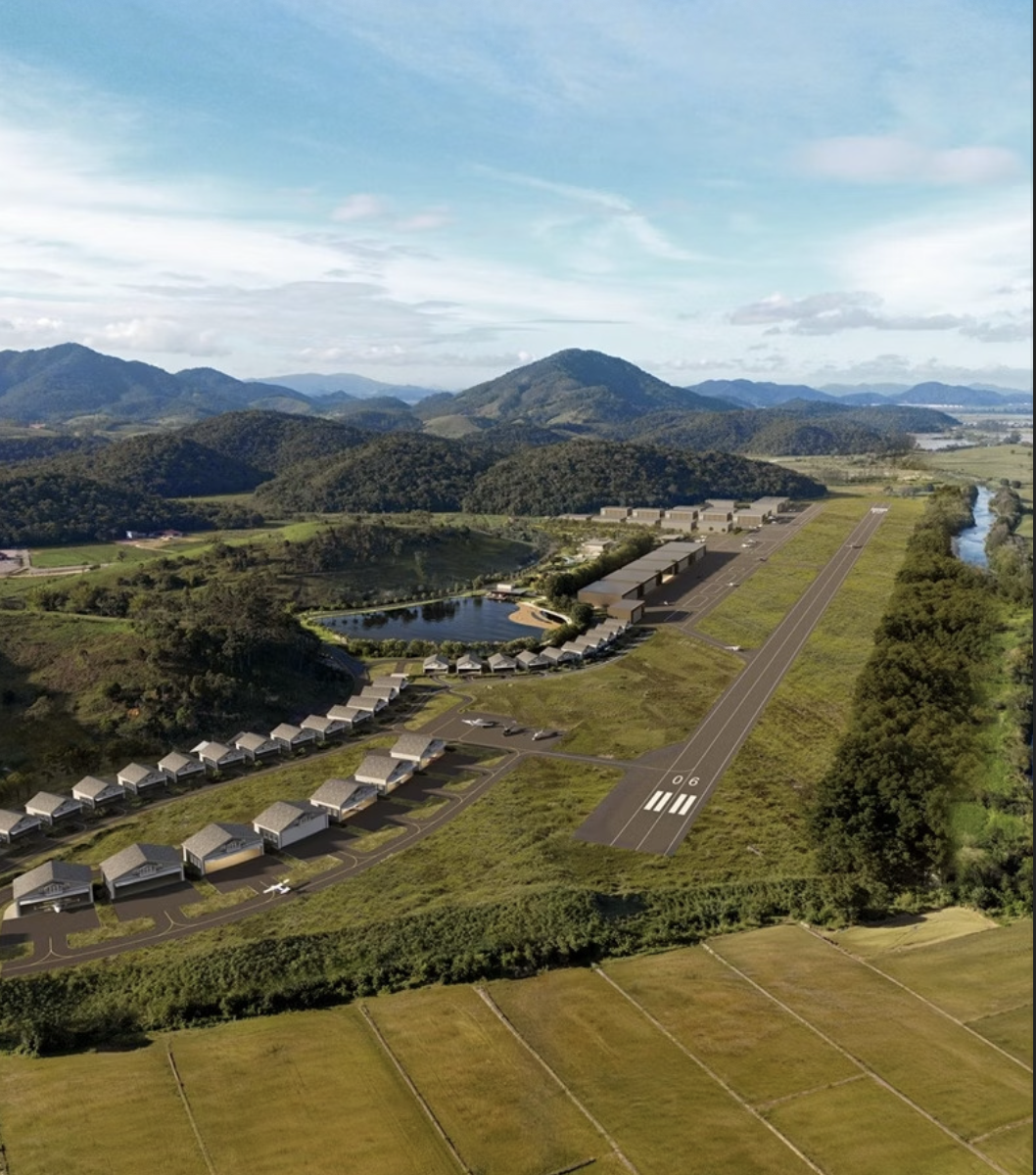 Vista aérea do complexo da Airport Experience - Overlife Club com hangares, pista de pouso e montanhas ao fundo