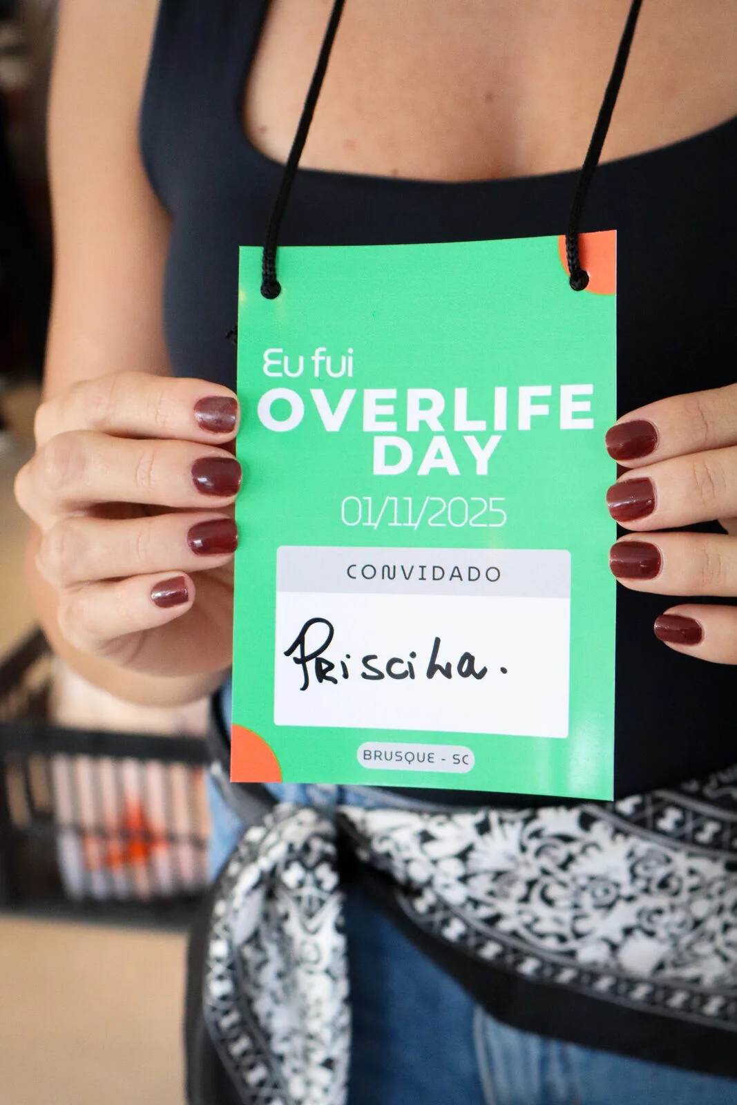 Convidada segurando credencial do Overlife Day 2025 em Brusque - SC