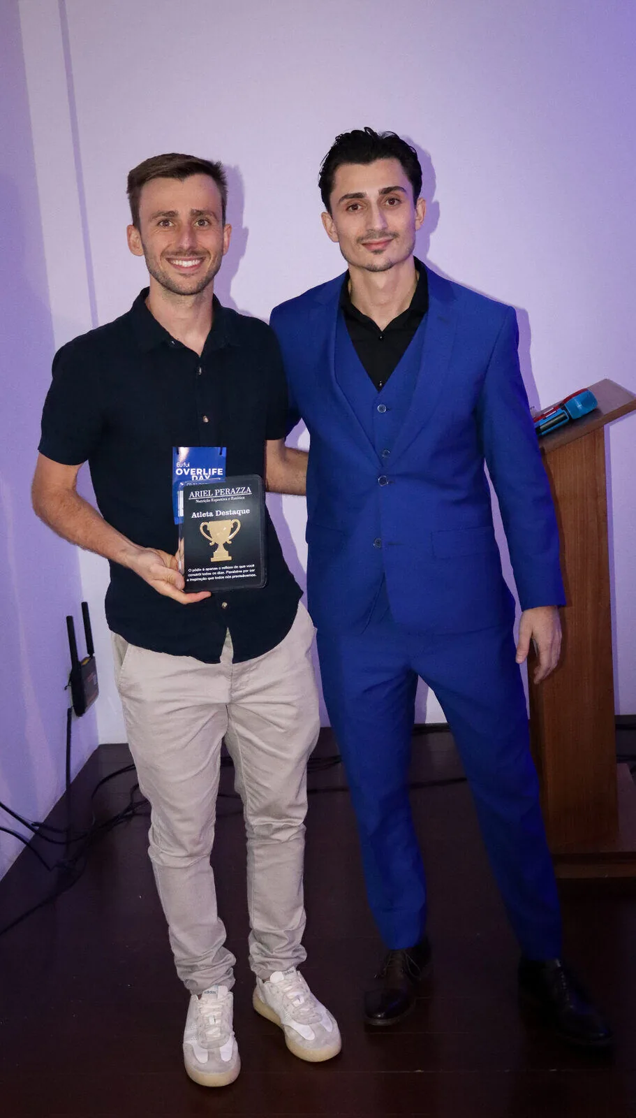 Atleta destaque recebendo placa de reconhecimento ao lado de Ariel Perazza no Overlife Day 2025